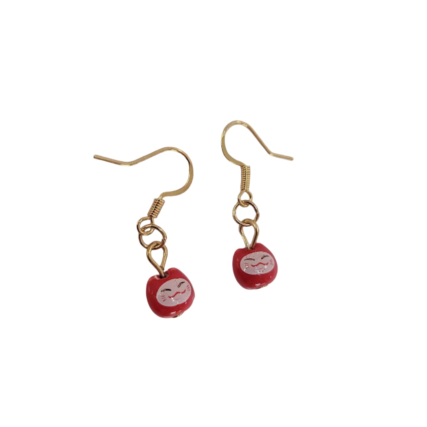 Pair of earrings with red beads and gold hooks on a light gray background