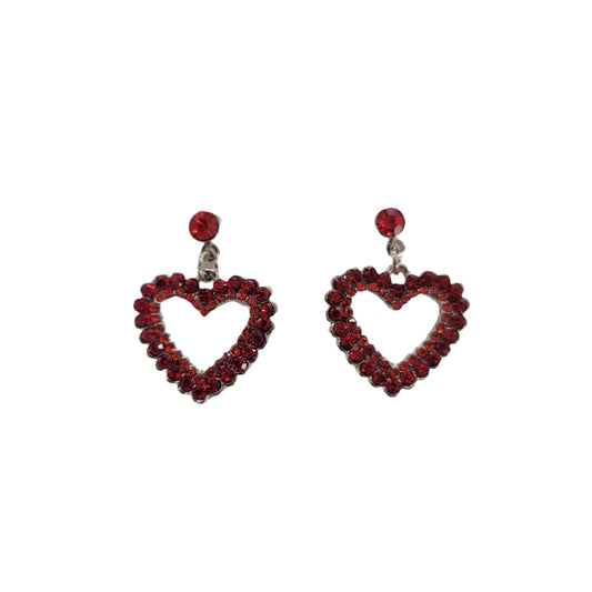 Heart-shaped earrings with red gemstones on a branded card against a reflective surface.